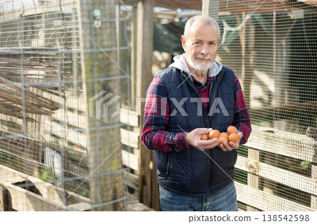 Eldery man with chicken eggs in hen house Eldery man with chicken eggs in hen house 138542598