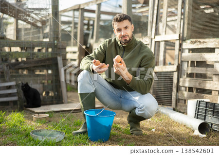 Positive man stands and holds in hands palms few fresh chicken eggs Positive man stands and holds in hands palms few fresh chicken eggs 138542601