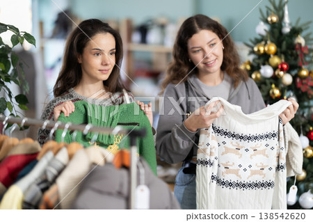 Young girls choosing sweater in clothing store during Christmas Young girls choosing sweater in clothing store during Christmas 138542620