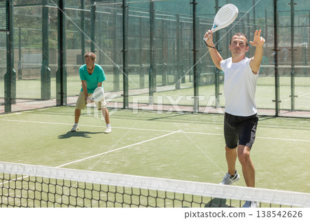 Young and adult men playing doubles padel 138542626