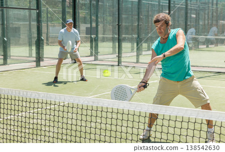 Two adult men playing doubles padel 138542630