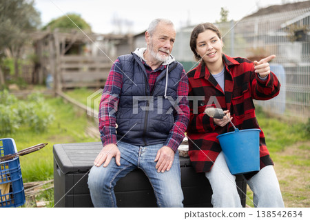 Young woman and elderly man talking in garden Young woman and elderly man talking in garden 138542634