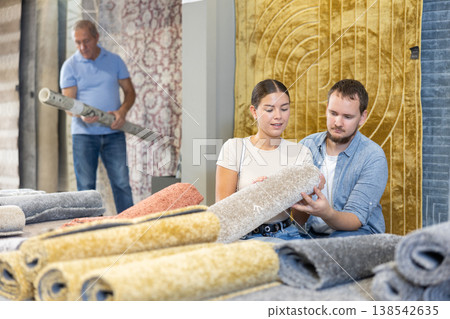 On territory of exhibition hall, husband and wife inspect carpets On territory of exhibition hall, husband and wife inspect carpets 138542635