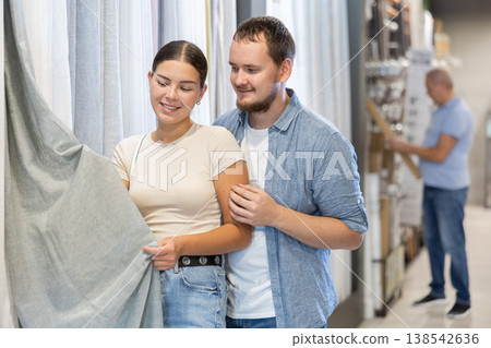 Couple man and woman choosing curtain in store Couple man and woman choosing curtain in store 138542636