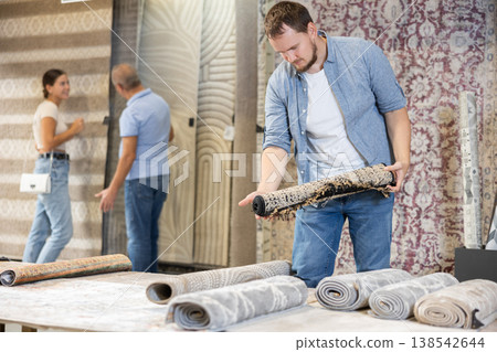 On territory of exhibition hall, guy inspect carpets On territory of exhibition hall, guy inspect carpets 138542644