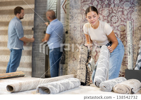 On territory of exhibition hall, girl inspect carpets On territory of exhibition hall, girl inspect carpets 138542732