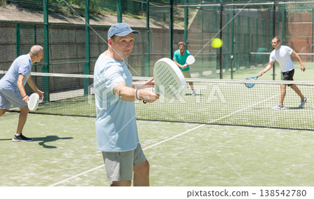Adult and elderly men playing padel against two men Adult and elderly men playing padel against two men 138542780