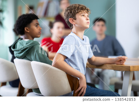 Teenage boy watching presentation while sitting with classmates in classroom Teenage boy watching presentation while sitting with classmates in classroom 138542853
