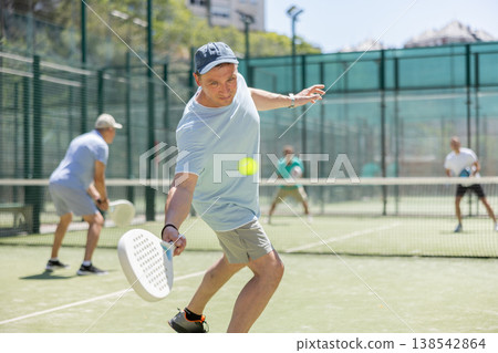 Padel game - man with partners plays on court Padel game - man with partners plays on court 138542864