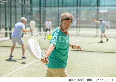 Adult and elderly men playing padel against two men Adult and elderly men playing padel against two men 138542884