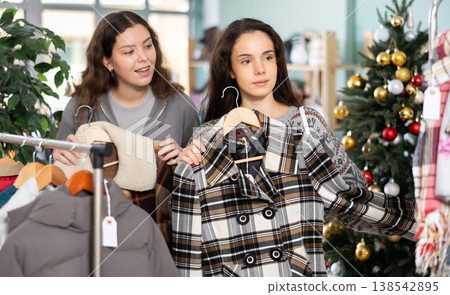 Two girls client pick up and choose clothes, is busy coat or jacket, New Year shopping Two girls client pick up and choose clothes, is busy coat or jacket, New Year shopping 138542895