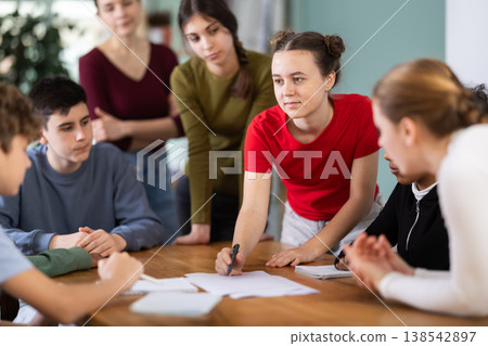 At round table meeting, teen participants discuss problem and try to find solution, teacher watching At round table meeting, teen participants discuss problem and try to find solution, teacher watching 138542897