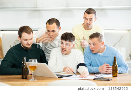 Group of football fans drinking beer and watching football match on laptop at home Group of football fans drinking beer and watching football match on laptop at home 138542923