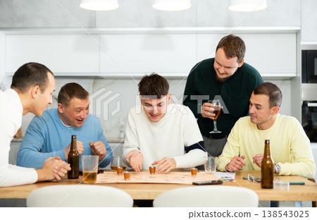 Male friends playing fun drinking board game at bachelor party Male friends playing fun drinking board game at bachelor party 138543025