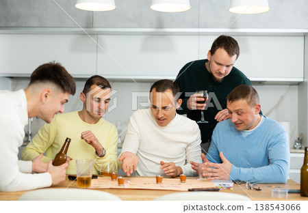 Group of cheerful men engaged in alcohol-fueled board game Group of cheerful men engaged in alcohol-fueled board game 138543066