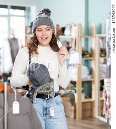 Young girl choosing winter hat during shopping in large clothing store Young girl choosing winter hat during shopping in large clothing store 138543093