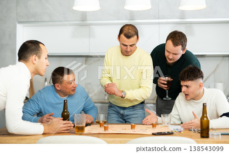 Male friends playing fun drinking board game at bachelor party 138543099