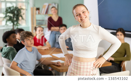 Joyful teenage girl standing in classroom 138543102