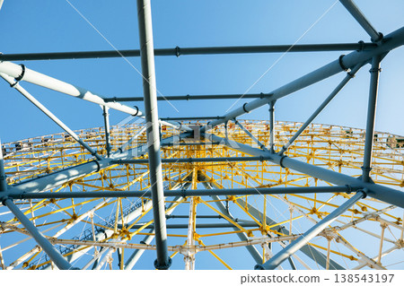Wide angle view looking up into the radial symmetry of the yellow and blue metal giant wheel framework Wide angle view looking up into the radial symmetry of the yellow and blue metal giant wheel framework 138543197