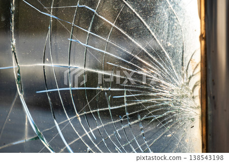 Close-up spiderweb fracture pattern of cracked tempered glass backlit by warm sunlight Close-up spiderweb fracture pattern of cracked tempered glass backlit by warm sunlight 138543198