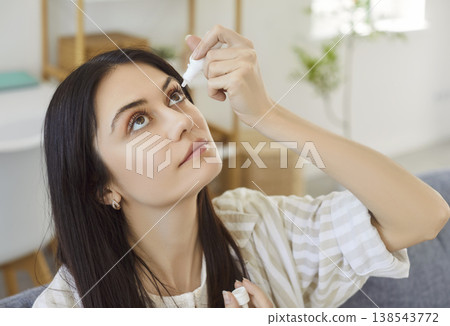 Woman using medical eyes drops suffering from dry eyes syndrome or curing ophthalmology disease Woman using medical eyes drops suffering from dry eyes syndrome or curing ophthalmology disease 138543772
