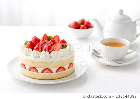 一塊完整的草莓蛋糕和一杯茶，背景是白色。 138544382
