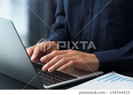 A business person using a laptop at their office desk. Close-up of hands and keyboard. A business person using a laptop at their office desk. Close-up of hands and keyboard. 138544425