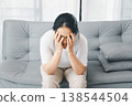 Depressed woman sitting on sofa at home with face in hands, stressed and anxious. Mental health sadness, burnout, loneliness concept for therapy, support, awareness campaigns, copy space. depressed 138544504