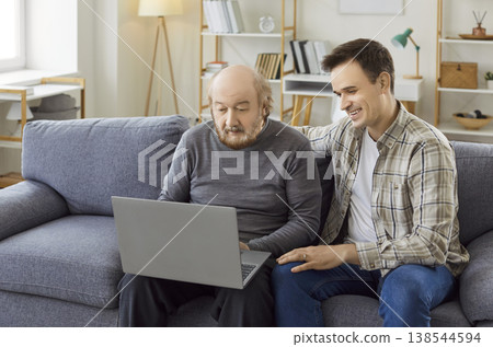 Young man helping adult son teaching interested mature senior father using laptop computer 138544594