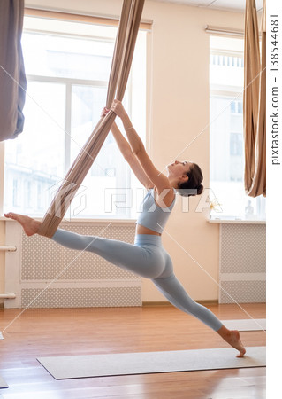 Woman fitness. Stretching exercise. Athlete doing fly yoga split pose holding fabric hammock straps for support flexibility workout. 138544681