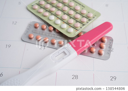 Pregnancy test and condom for female on calendar, ovulation day. Pregnancy test and condom for female on calendar, ovulation day. 138544806