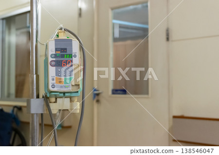 Close up of medical infusion pump attached to IV stand in hospital room with soft background and copy space representing healthcare treatment monitoring and patient care environment Close up of medical infusion pump attached to IV stand in hospital room with soft background and copy space representing healthcare treatment monitoring and patient care environment 138546047