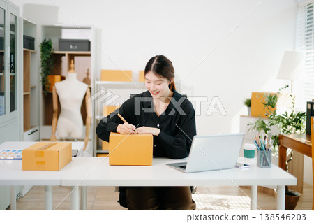 Startup small business SME, Entrepreneur owner woman using smartphone or tablet taking receive and checking online purchase shopping order to preparing pack product box. 138546203