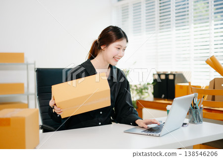 Young businesswoman managing online sales and shipping from a modern home office. Perfect for showcasing technology Young businesswoman managing online sales and shipping from a modern home office. Perfect for showcasing technology 138546206