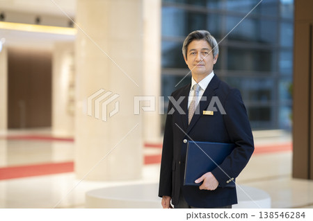 一位高級商務人士戴著名牌,微笑著直視鏡頭,這是他的肖像照。 一位高級商務人士戴著名牌,微笑著直視鏡頭,這是他的肖像照。 138546284