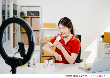 Asian beauty influencer reviewing skincare product on camera with ring light and smartphone for social media marketing, reflecting modern lifestyle Asian beauty influencer reviewing skincare product on camera with ring light and smartphone for social media marketing, reflecting modern lifestyle 138546340