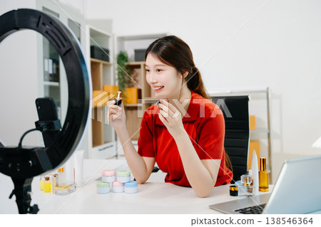 The scene highlights asian woman demonstrating lipstick and cosmetics for beauty advertising and ecommerce, reflecting modern content creation in a clean indoor studio environment. The scene highlights asian woman demonstrating lipstick and cosmetics for beauty advertising and ecommerce, reflecting modern content creation in a clean indoor studio environment. 138546364