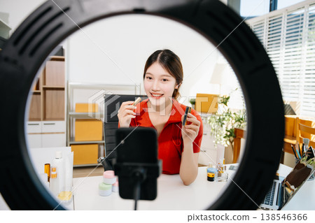 The scene highlights asian woman demonstrating lipstick and cosmetics for beauty advertising and ecommerce, reflecting modern content creation in a clean indoor studio environment. 138546366