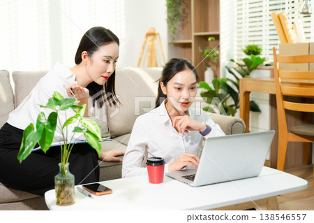 Two businesswomen discussing ideas while working with laptop at home office. Remote work, teamwork, collaboration, startup meeting and modern business lifestyle. Two businesswomen discussing ideas while working with laptop at home office. Remote work, teamwork, collaboration, startup meeting and modern business lifestyle. 138546557