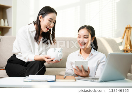 Smiling couple managing savings and budget at home with piggy bank, laptop and calculator. Personal finance, investment planning and smart money management Smiling couple managing savings and budget at home with piggy bank, laptop and calculator. Personal finance, investment planning and smart money management 138546565
