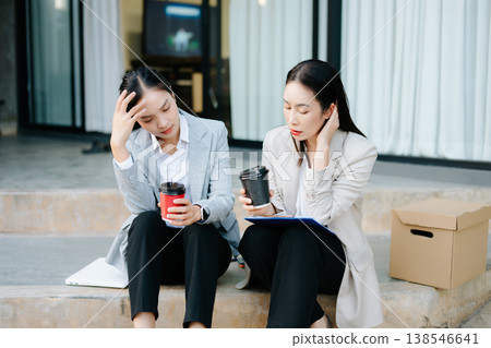 Stressed businesswoman holding a box after job loss, supported by colleague. Workplace stress, unemployment, burnout, mental health, corporate crisis and support concept. Stressed businesswoman holding a box after job loss, supported by colleague. Workplace stress, unemployment, burnout, mental health, corporate crisis and support concept. 138546641