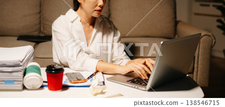 Stressed Asian woman using calculator and laptop for financial accounting and tax report late at night at home. Stressed Asian woman using calculator and laptop for financial accounting and tax report late at night at home. 138546715