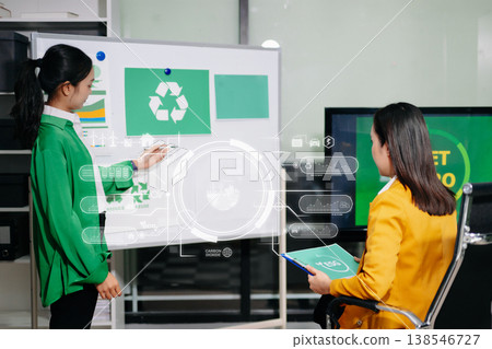 Businesswomen discussing net zero sustainability strategy with renewable energy models, solar panels and green office concepts, representing eco friendly business 138546727