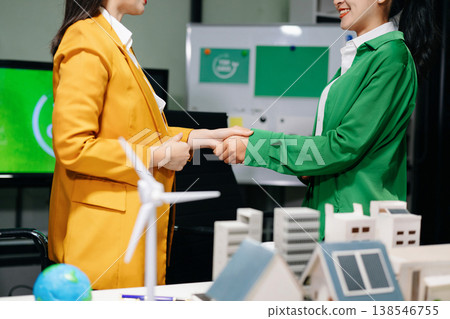 Businesswomen shaking hands in a green office with renewable energy models, net zero and ESG concept, sustainability, clean energy Businesswomen shaking hands in a green office with renewable energy models, net zero and ESG concept, sustainability, clean energy 138546755