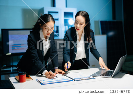 Two professional businesswomen analyzing reports and planning strategy at office desk. Teamwork, collaboration, management, consulting and modern corporate workplace. 138546778