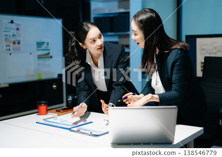Two professional businesswomen analyzing reports and planning strategy at office desk. Teamwork, collaboration, management, consulting and modern corporate workplace. 138546779