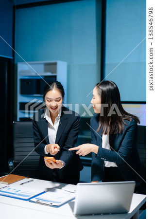 Two professional businesswomen analyzing reports and planning strategy at office desk. Teamwork, collaboration, management, consulting and modern corporate workplace. Two professional businesswomen analyzing reports and planning strategy at office desk. Teamwork, collaboration, management, consulting and modern corporate workplace. 138546798