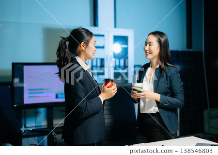 Two businesswomen having a friendly discussion during coffee break in modern office. Professional teamwork, collaboration, communication, startup and corporate workplace lifestyle. Two businesswomen having a friendly discussion during coffee break in modern office. Professional teamwork, collaboration, communication, startup and corporate workplace lifestyle. 138546803