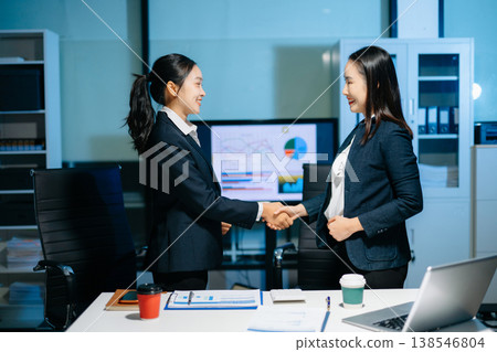 Two businesswomen shaking hands in modern office after agreement. Professional partnership, corporate teamwork, trust, negotiation, success and business collaboration. Two businesswomen shaking hands in modern office after agreement. Professional partnership, corporate teamwork, trust, negotiation, success and business collaboration. 138546804