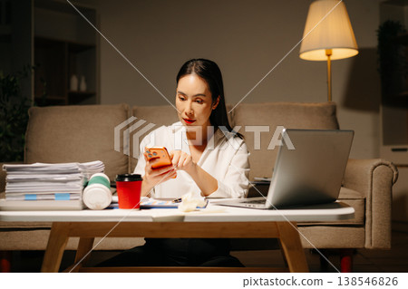 Stressed Asian woman using calculator and laptop for financial accounting and tax report late at night at home. 138546826